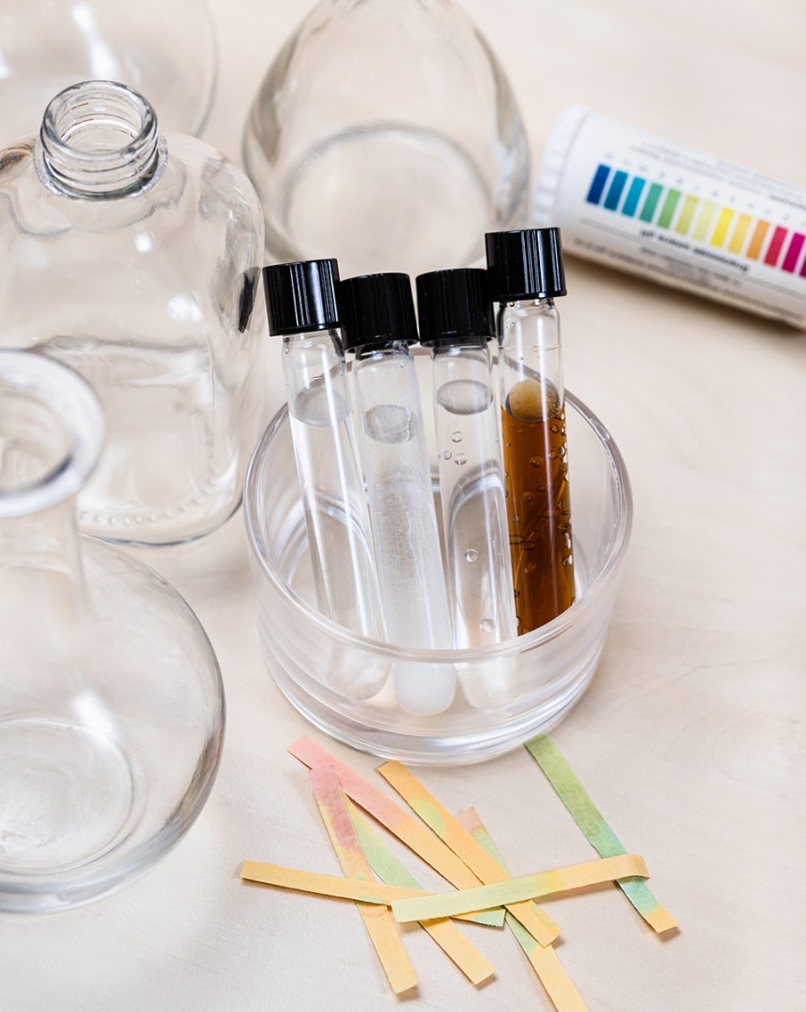 test tubes with various solutions, bottles and used indicators on light desk